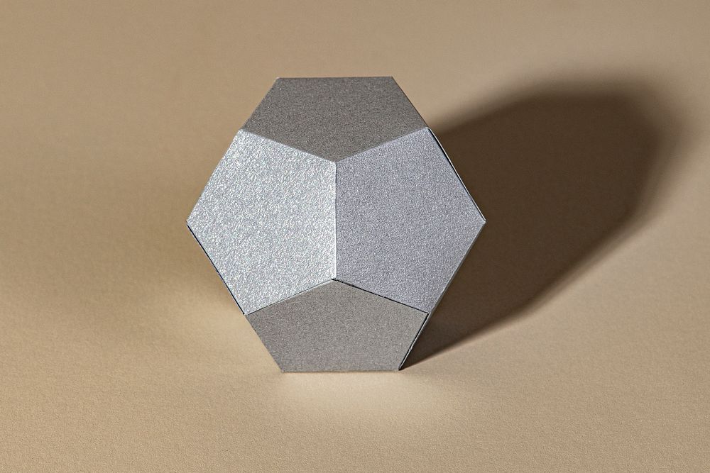 3D silver pentagon shaped paper craft on a beige background
