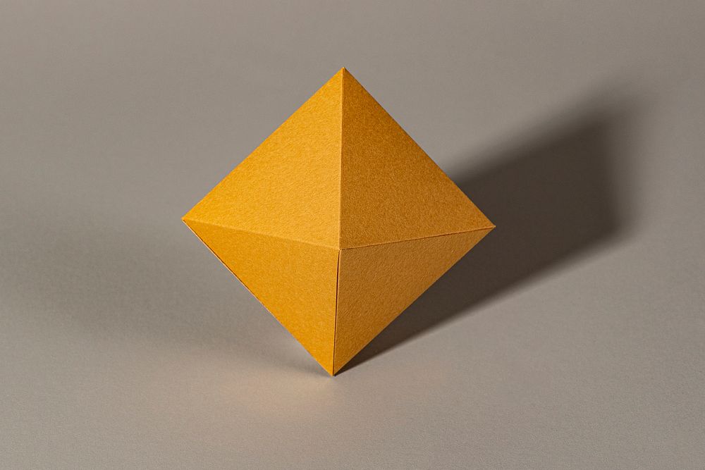 3D golden pyramid paper craft on a beige background