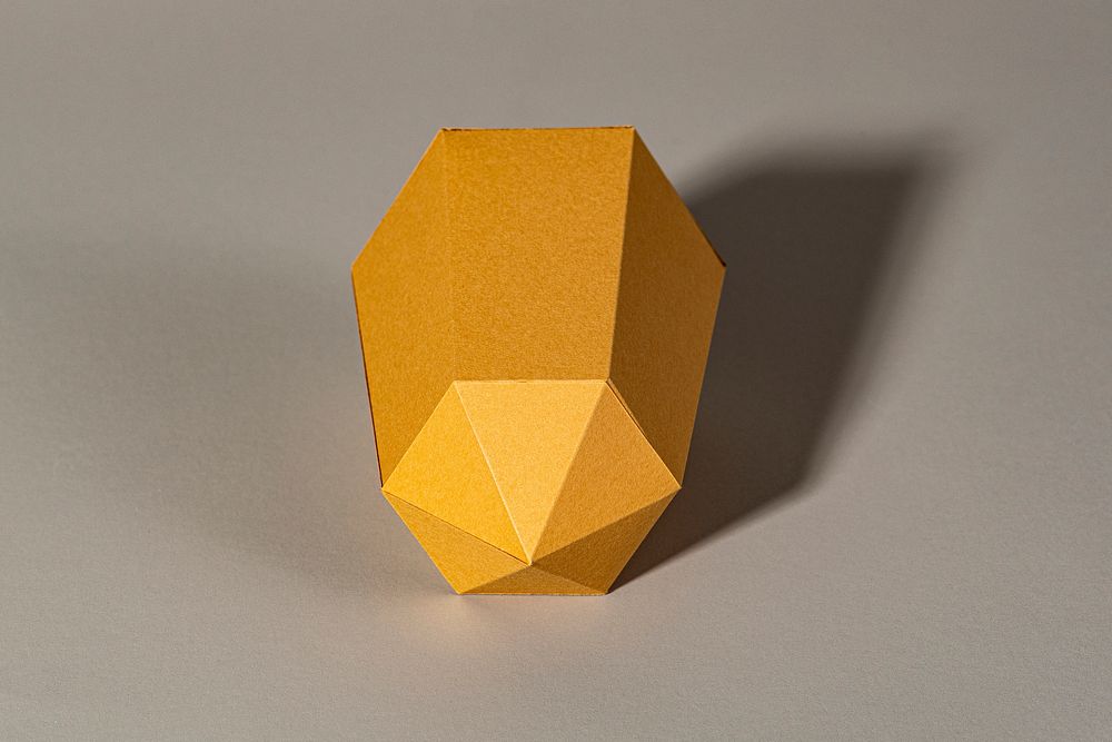 Golden hexagonal prism paper craft on a beige background