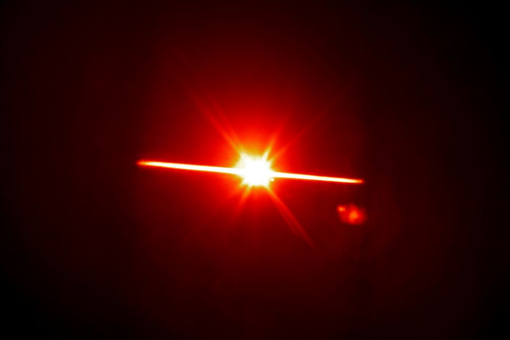Red lens flare effect design element on a black background
