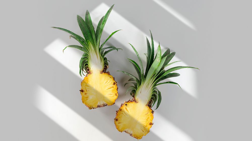Fresh pineapple cut in half on off white background