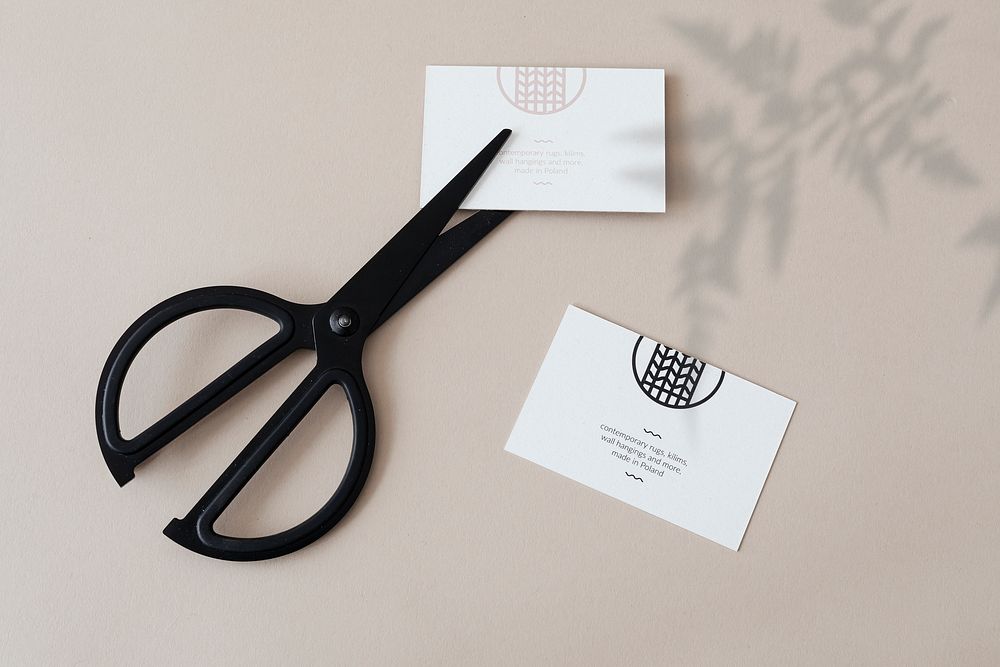 White business cards with scissors on a concrete wall mockup