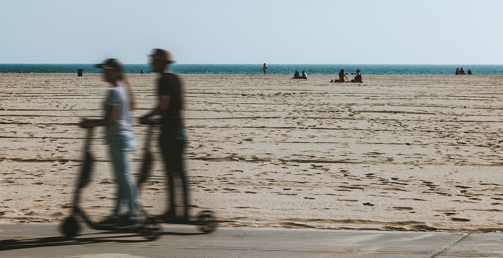 Couple riding a scooter by the beach