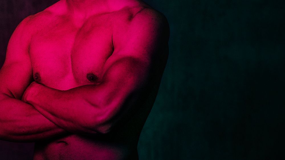 Portrait of a sportive muscular topless man with arm crossed pink filter