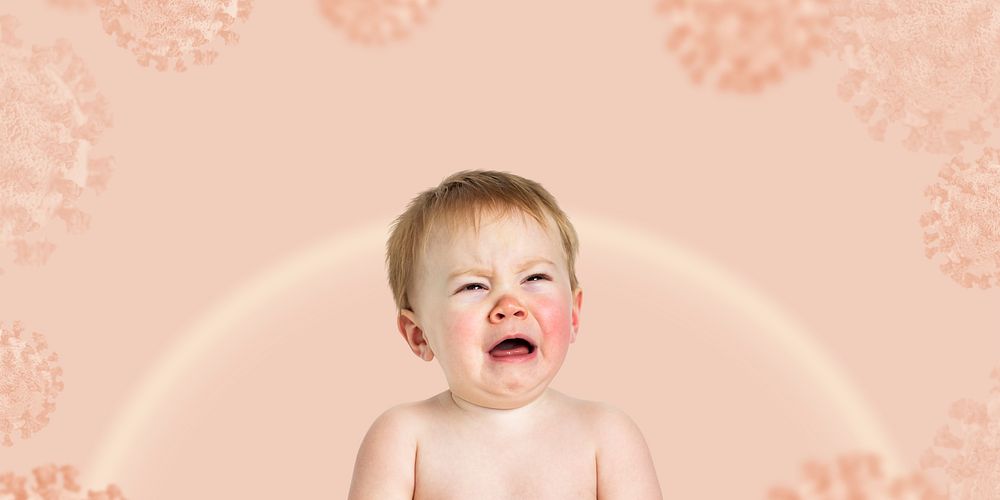 Crying baby on a pink coronavirus contaminated background banner