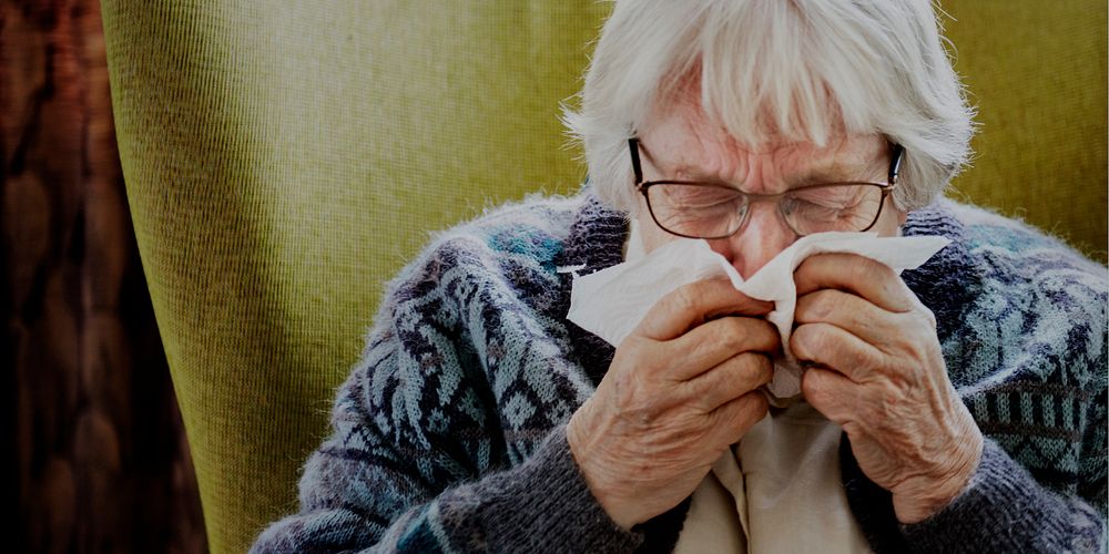 Senior woman sneezing and showing covid-19 symptoms
