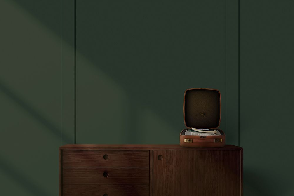 Vintage vinyl record player on wooden sideboard in green wall background