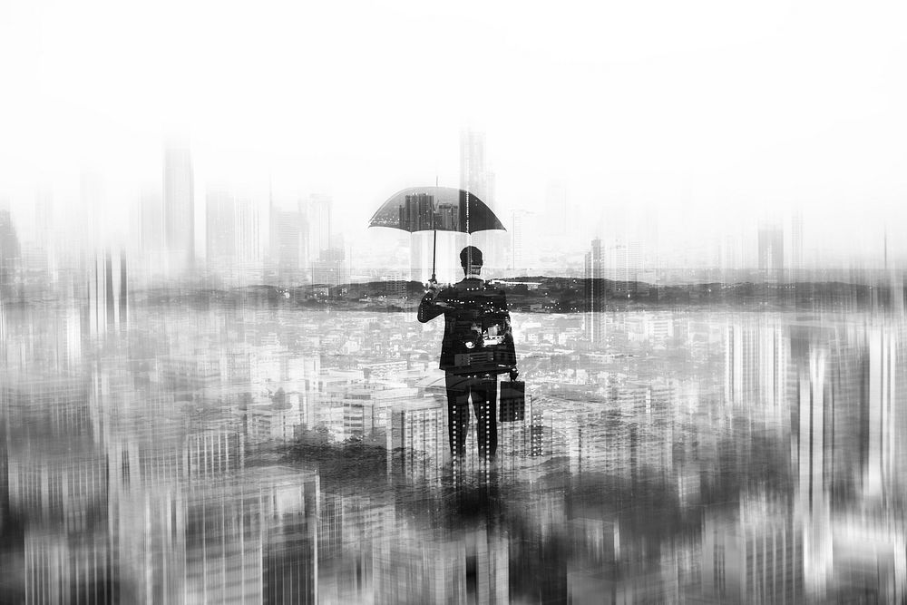 Businessman in suit holding umbrella on city background monochrome