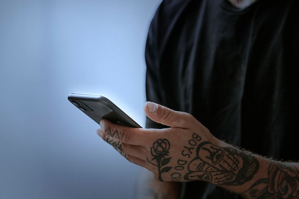 Tattooed man using smartphone for social media remix