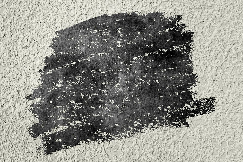 Black oil paint texture on a beige concrete wall