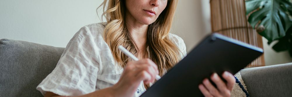 Woman using a stylus writing on a digital tablet  during coronavirus quarantine