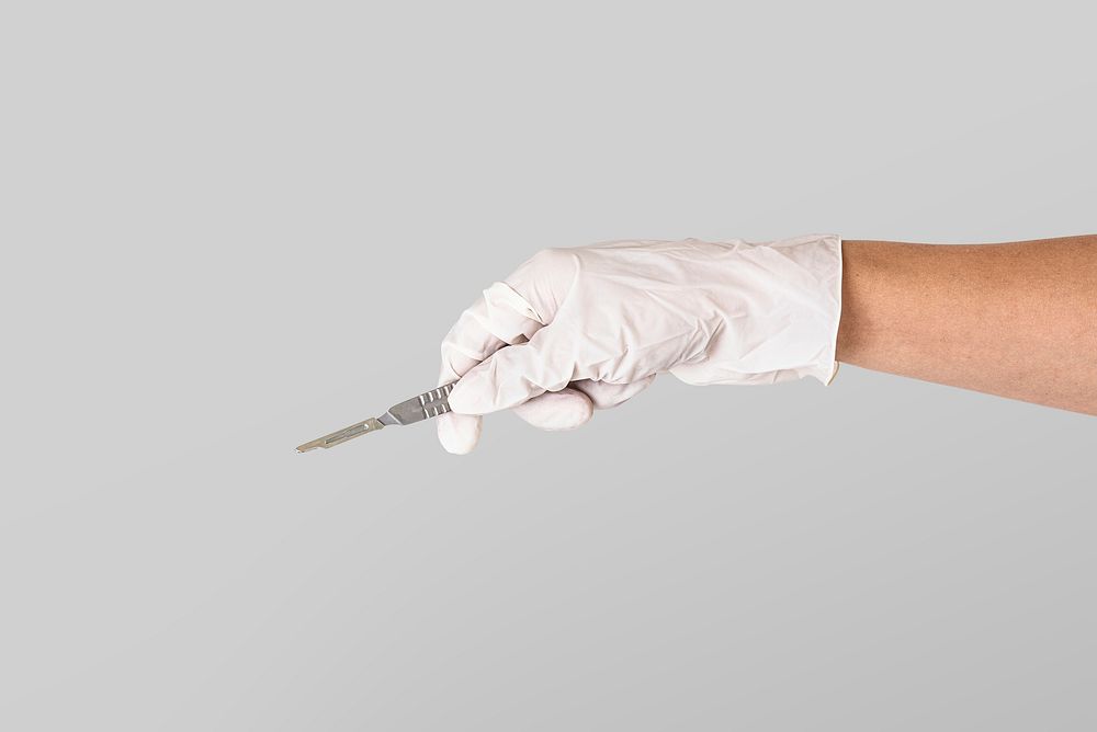 Doctor's hand in a white glove holding a scalpel