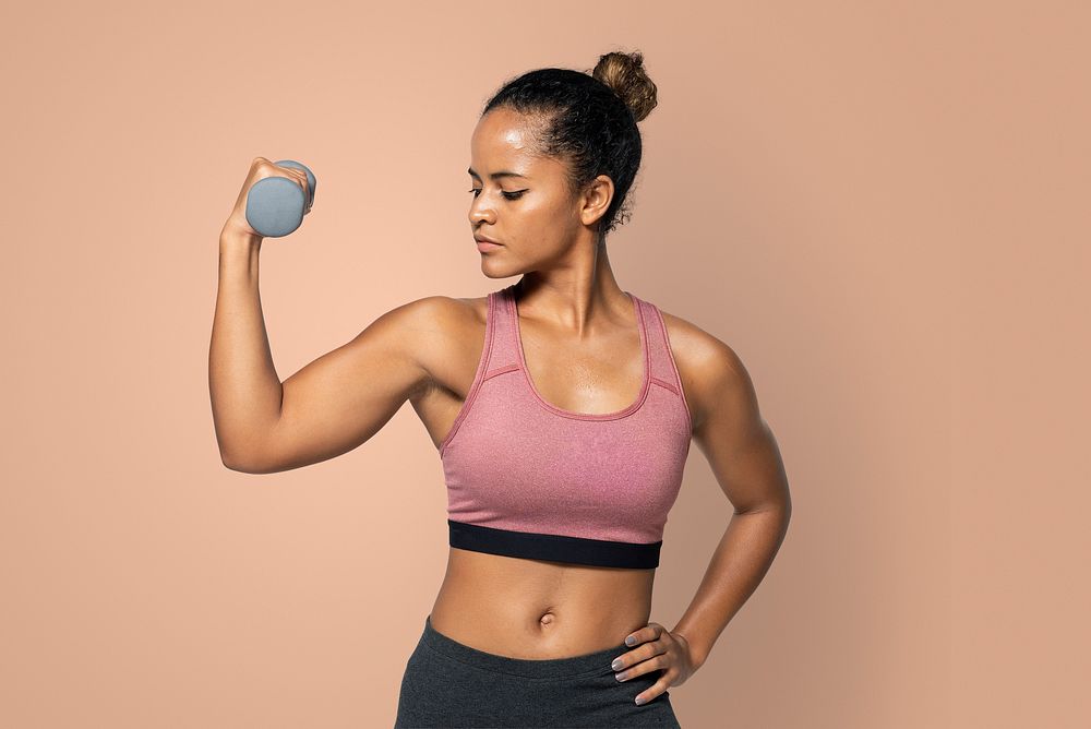Sporty woman lifting dumbbell weights in a blue background