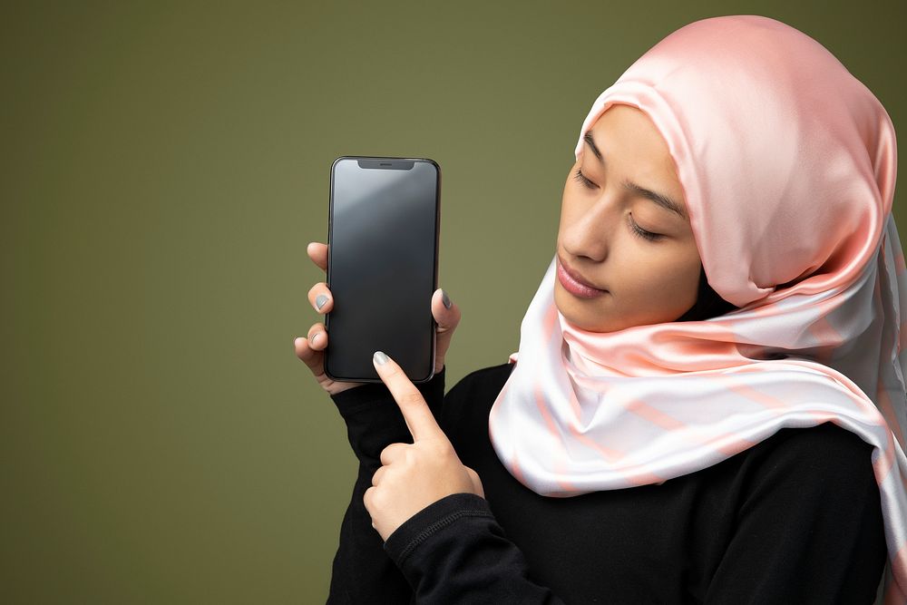 Muslim woman showing a mobile screen in a green background