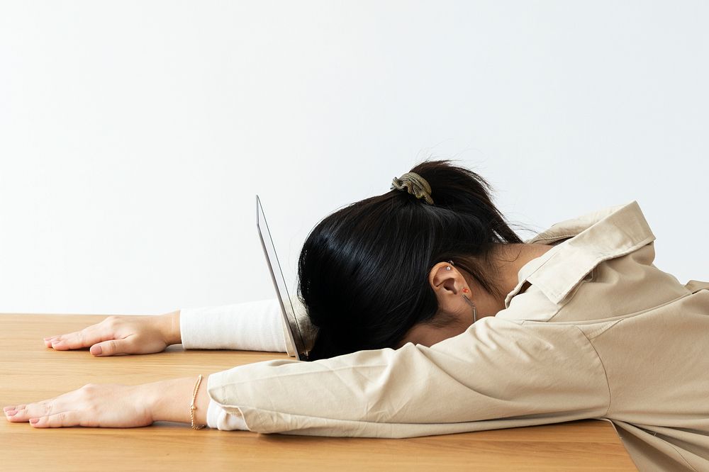 Exhausted Asian girl resting her head on a laptop