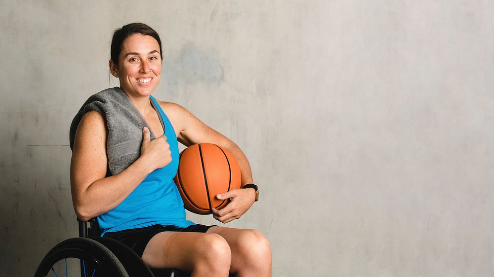 Happy female athlete in a wheelchair with a basketball 