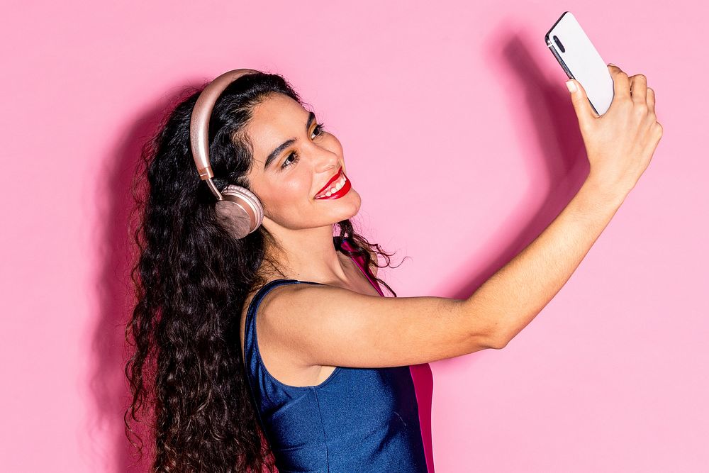 Woman wearing headphones and taking a selfie