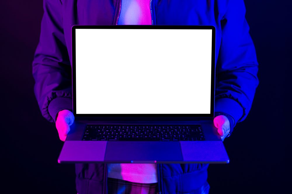 Man showing laptop blank screen in neon light