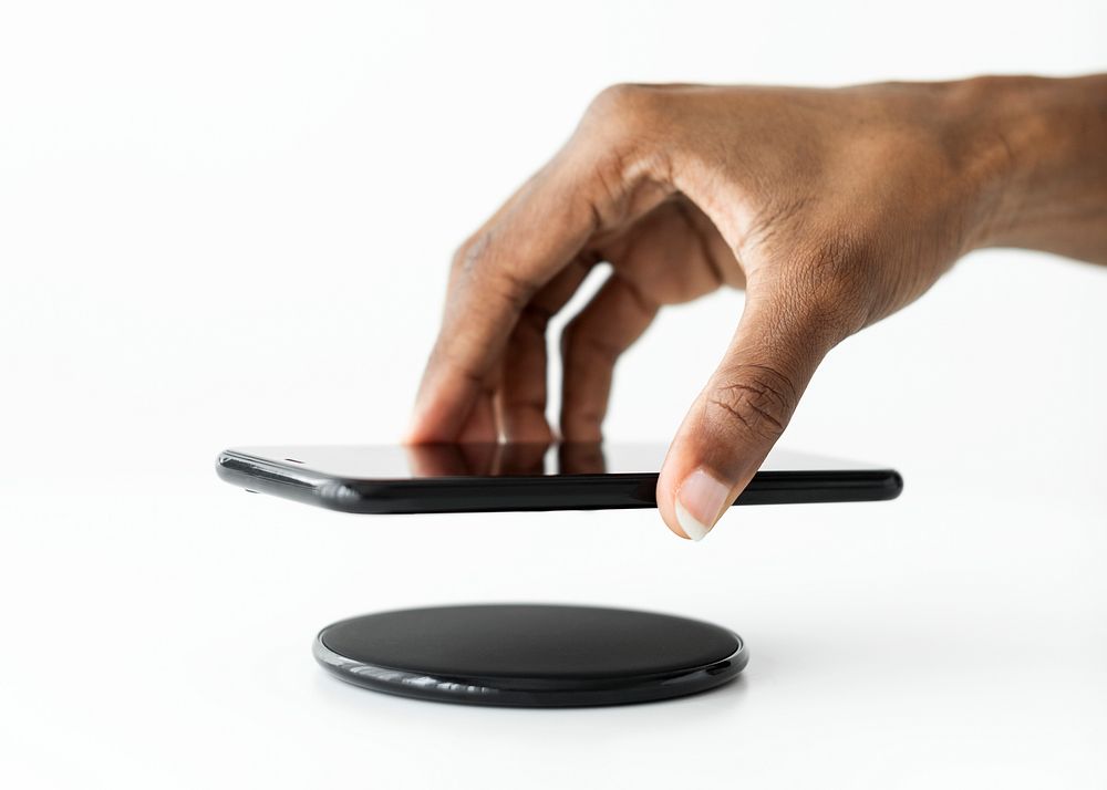 Hand connecting smartphone to wireless charger