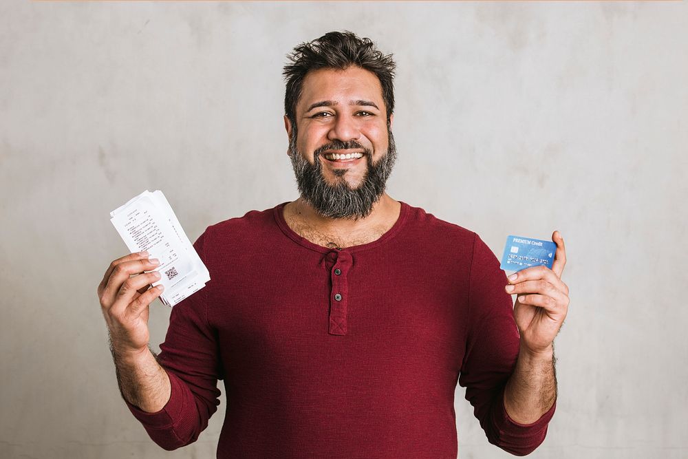 Happy senior Indian man holding his bills and a credit card