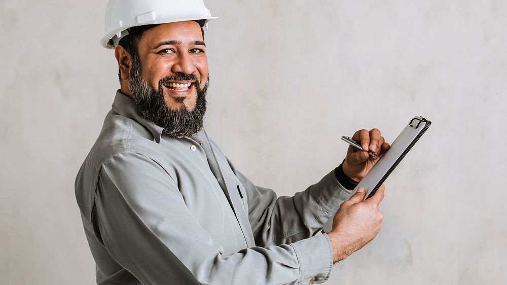 Indian engineer writing on a paper clipboard