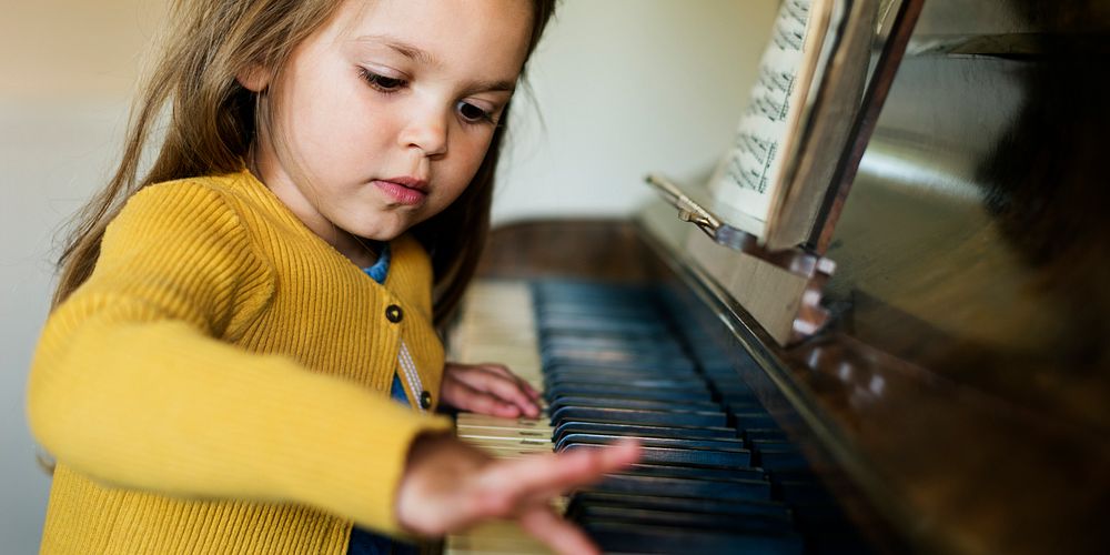 Cute little girl playing piano banner