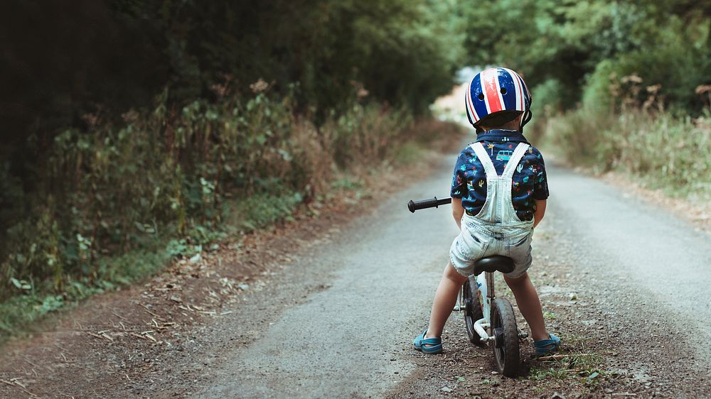 Little boy learning how to ride a bike in the forest