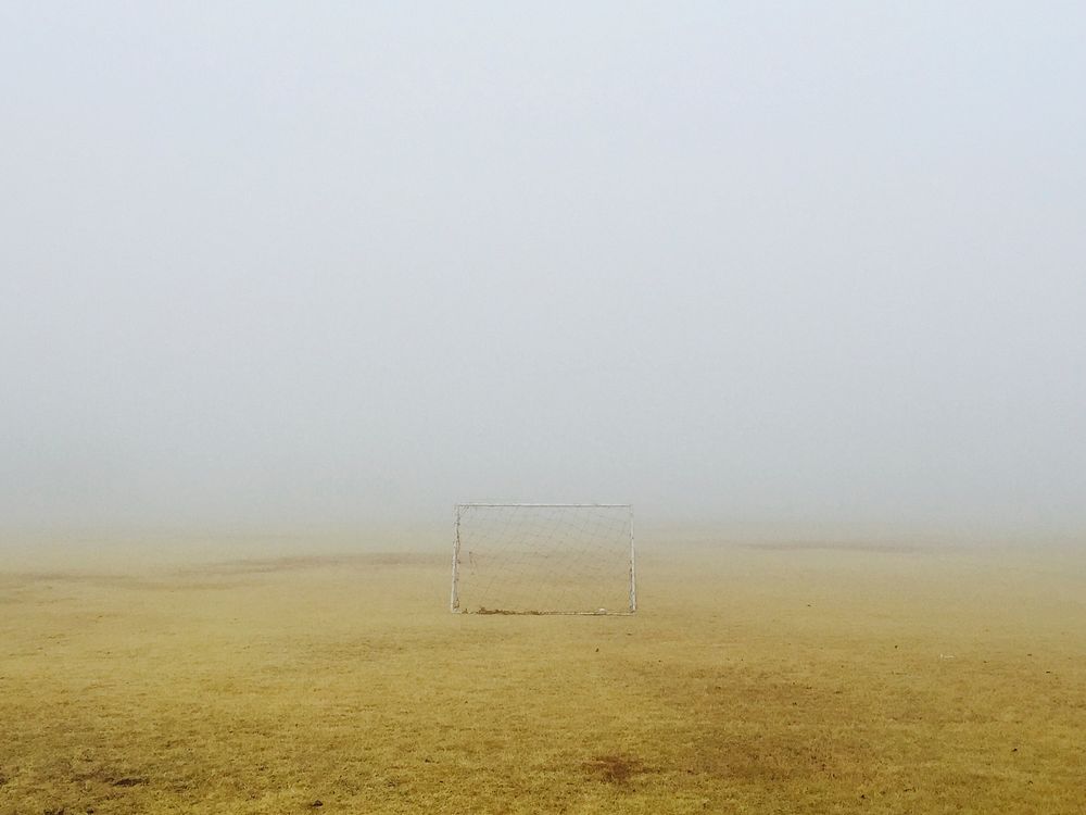 Small soccer goal sitting on the yellow scorched grass field on a foggy day. Original public domain image from Wikimedia…