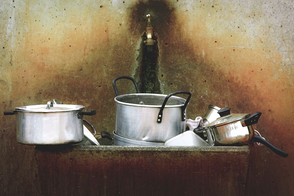 Silver pots and dishes in a dirty old sink with a small faucet. Original public domain image from Wikimedia Commons