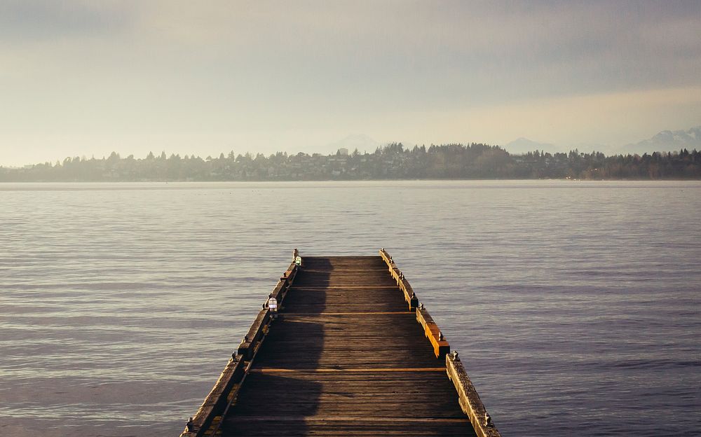 An empty wooden pier on a lake with a woody shore on the horizon. Original public domain image from Wikimedia Commons