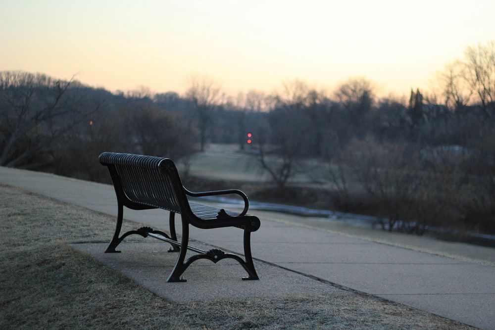 A black bench along an empty park lane during sunset. Original public domain image from Wikimedia Commons