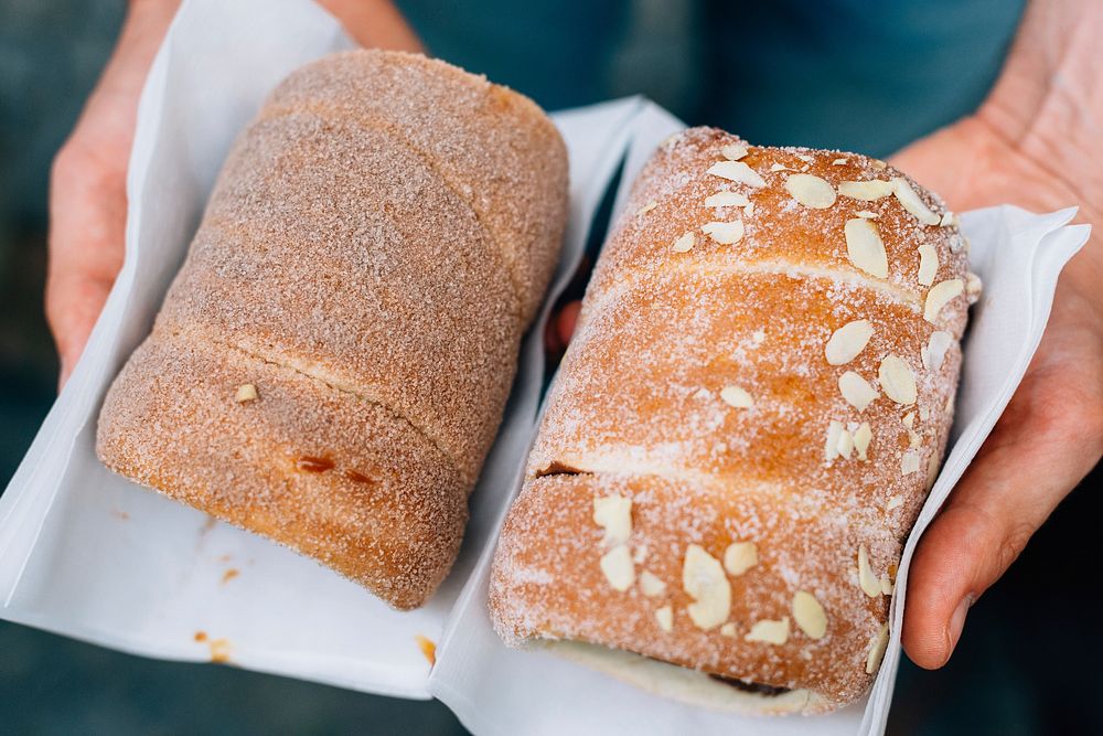 Hands hold two loaves of freshly baked sweet bread. Original public domain image from Wikimedia Commons