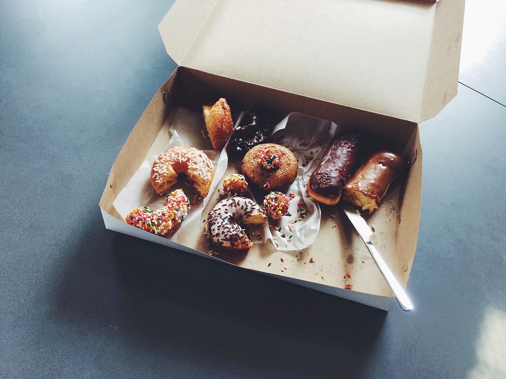 Box of half eaten donuts on an office break room table. Original public domain image from Wikimedia Commons