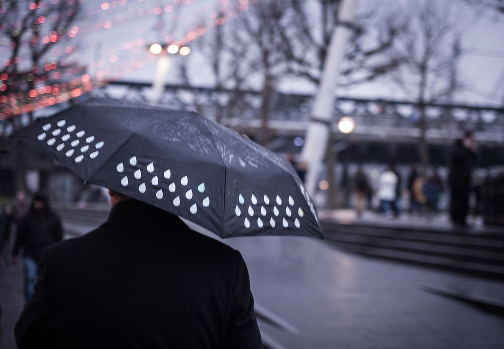 A blurry shot of a man with a wet black umbrella in London. Original public domain image from Wikimedia Commons