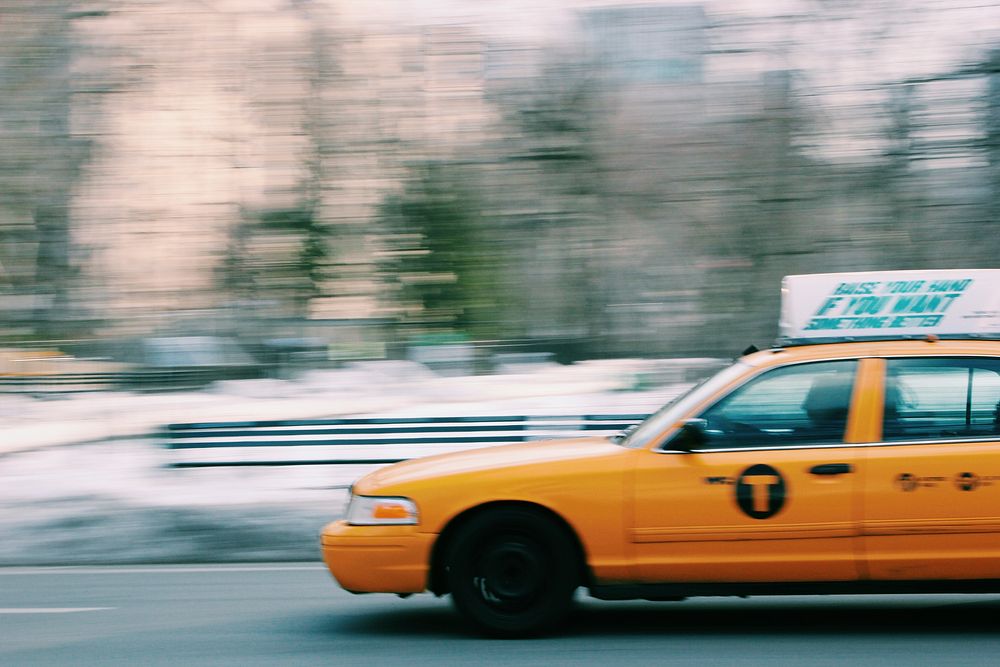 Yellow taxi in motion driving past Central Park in New York City. Original public domain image from Wikimedia Commons