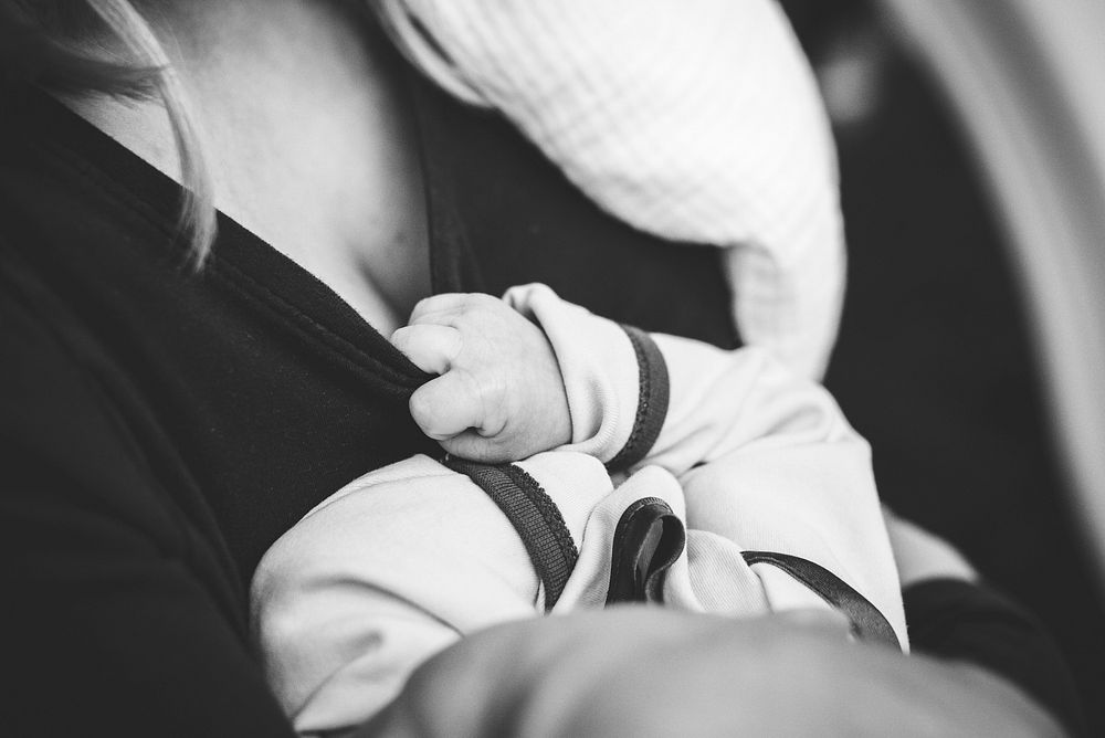 Black and white photo of mother holding baby in soft light. Original public domain image from Wikimedia Commons