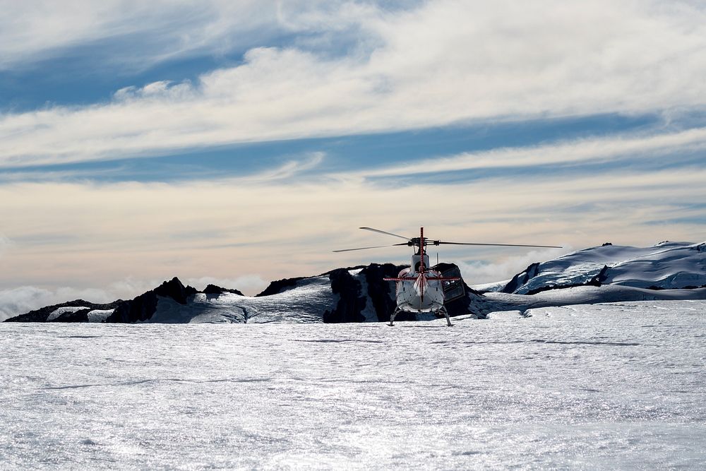 A helicopter sitting in a field of snow at Fox Glacier in New Zealand. Original public domain image from Wikimedia Commons