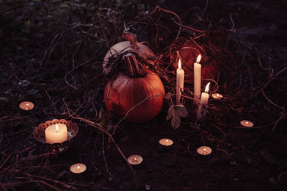 Pumpkins with branches on the ground with lit candles by them in Barcelo. Original public domain image from Wikimedia Commons