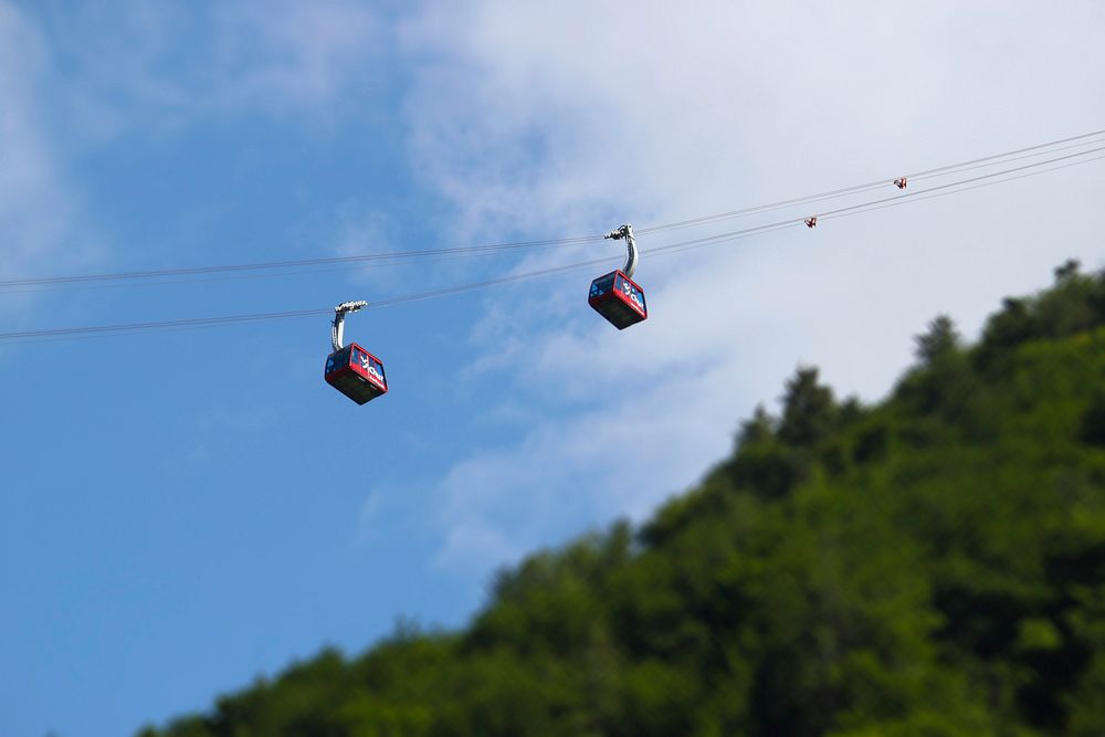 Tilt-shift view of cable cars ascneing up a mountain with clear blue skies in the background.. Original public domain image…