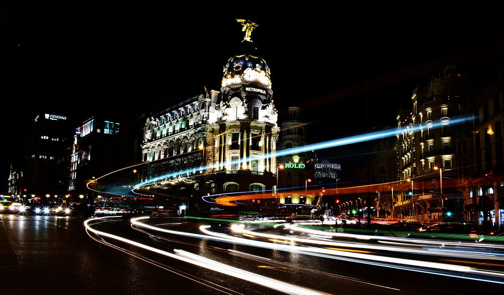 A dark shot of urban buildings lit up at night in Madrid. Original public domain image from Wikimedia Commons