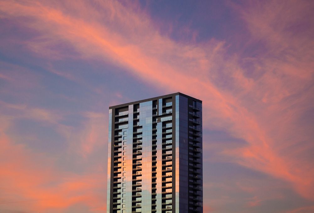 A skyscraper reflecting the purple and pink cloudy sky at sunset in Austin. Original public domain image from Wikimedia…