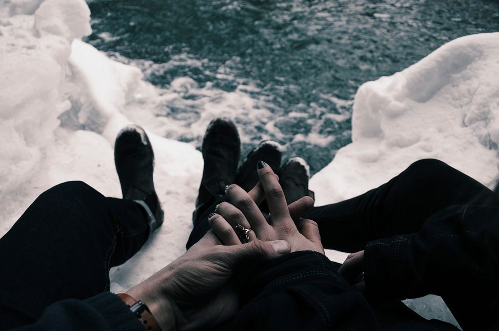 Couple with hands clasped while sitting on icy mountaintop overlooking water. Original public domain image from Wikimedia…