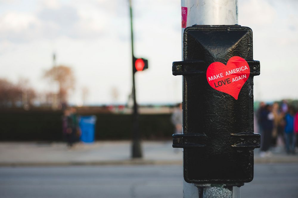 A red, heart-shaped sticker on a traffic post reads "Make America Love Again.". Original public domain image from Wikimedia…