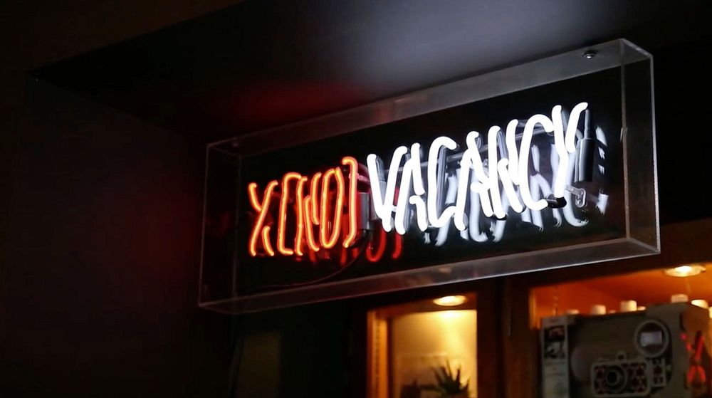 Neon "no vacancy" sign lit up by an urban motel at night. Original public domain image from Wikimedia Commons