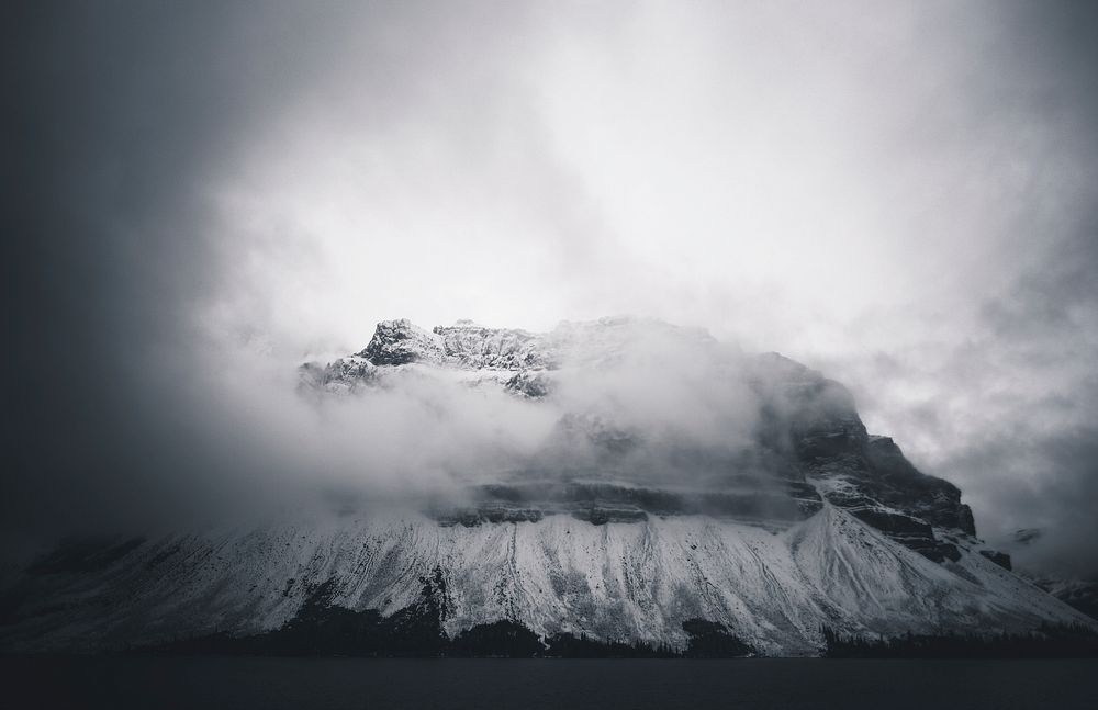 An ominous shot of a tall mountain shrouded in thick clouds in Banff. Original public domain image from Wikimedia Commons
