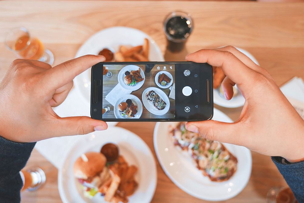 Person takes a picture of their brunch on their smartphone. Original public domain image from Wikimedia Commons
