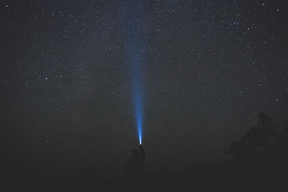 A man shines a flashlight into the starry night sky at Samuel de Champlain Provincial Park.. Original public domain image…