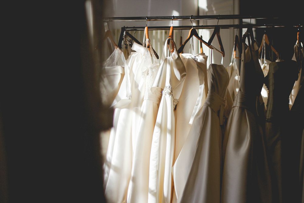 White and beige dresses on hangers in a store. Original public domain image from Wikimedia Commons