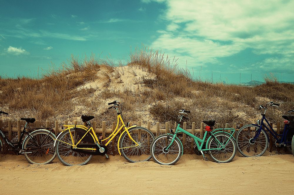 Colorful bicycles leaned on a wooden fence at the Formentera beach. Original public domain image from Wikimedia Commons
