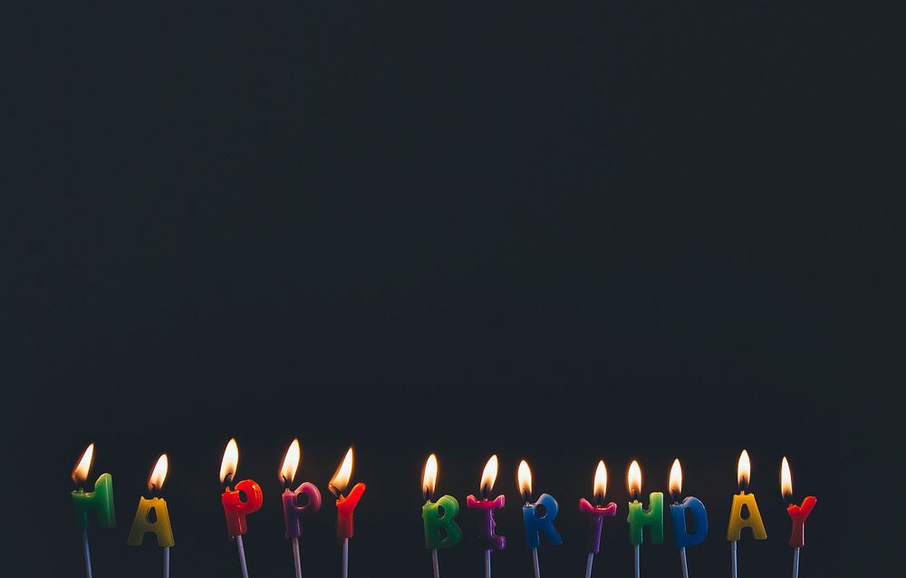 Happy birthday candles that are lit and melting. Original public domain image from Wikimedia Commons
